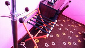 A chair with a black and orange frame, a small table with a black surface, and a patterned carpet with yellow and white flowers. - 25 Four Seasons Youth Hostel (Qingdao)