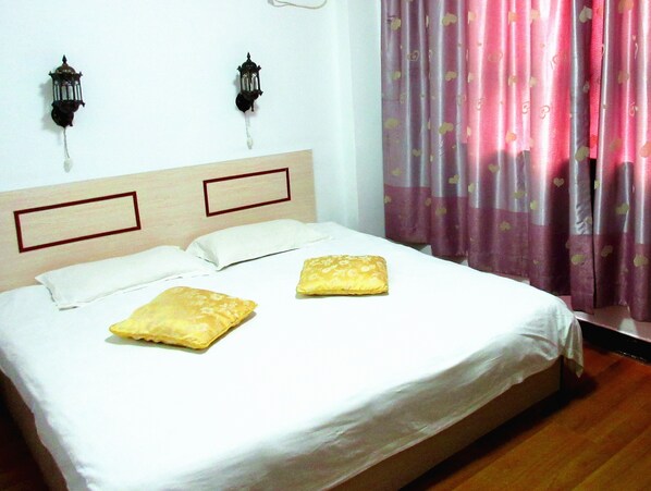 A bed with two pillows, a wooden headboard, and two wall-mounted light fixtures.