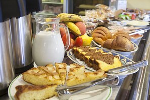 A buffet with various food items including pastries, fruits, and a pitcher of milk. - Hotel La Casa del Abuelo (Tapia de Casariego)