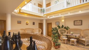 Un interior espacioso con mobiliario de mimbre, un comedor y un balcón con barandilla.