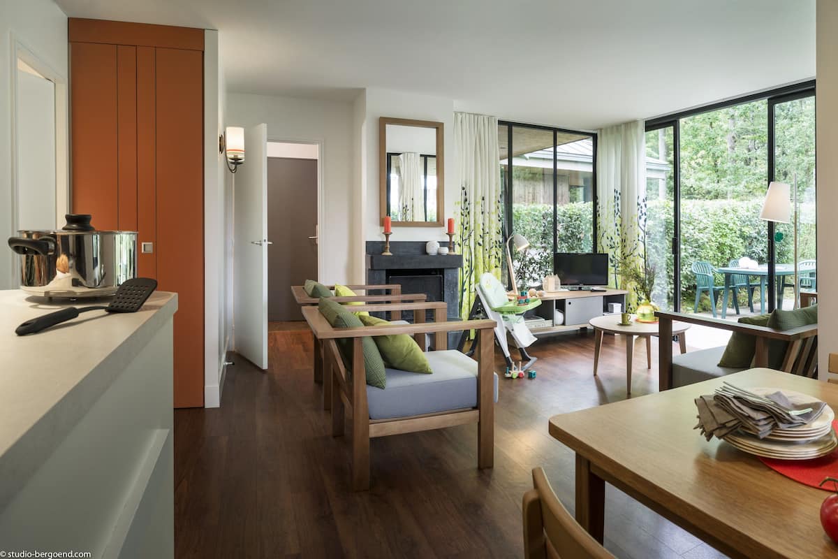 Eine moderne Küche mit Essbereich, großen Fenstern und Blick auf Grünflächen.