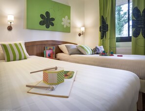 Two beds with striped pillows, a wooden headboard, and a floral artwork adorn this cozy space.