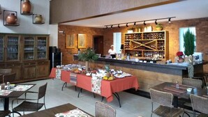 A restaurant with a long counter, wicker chairs, and a variety of dishes displayed.