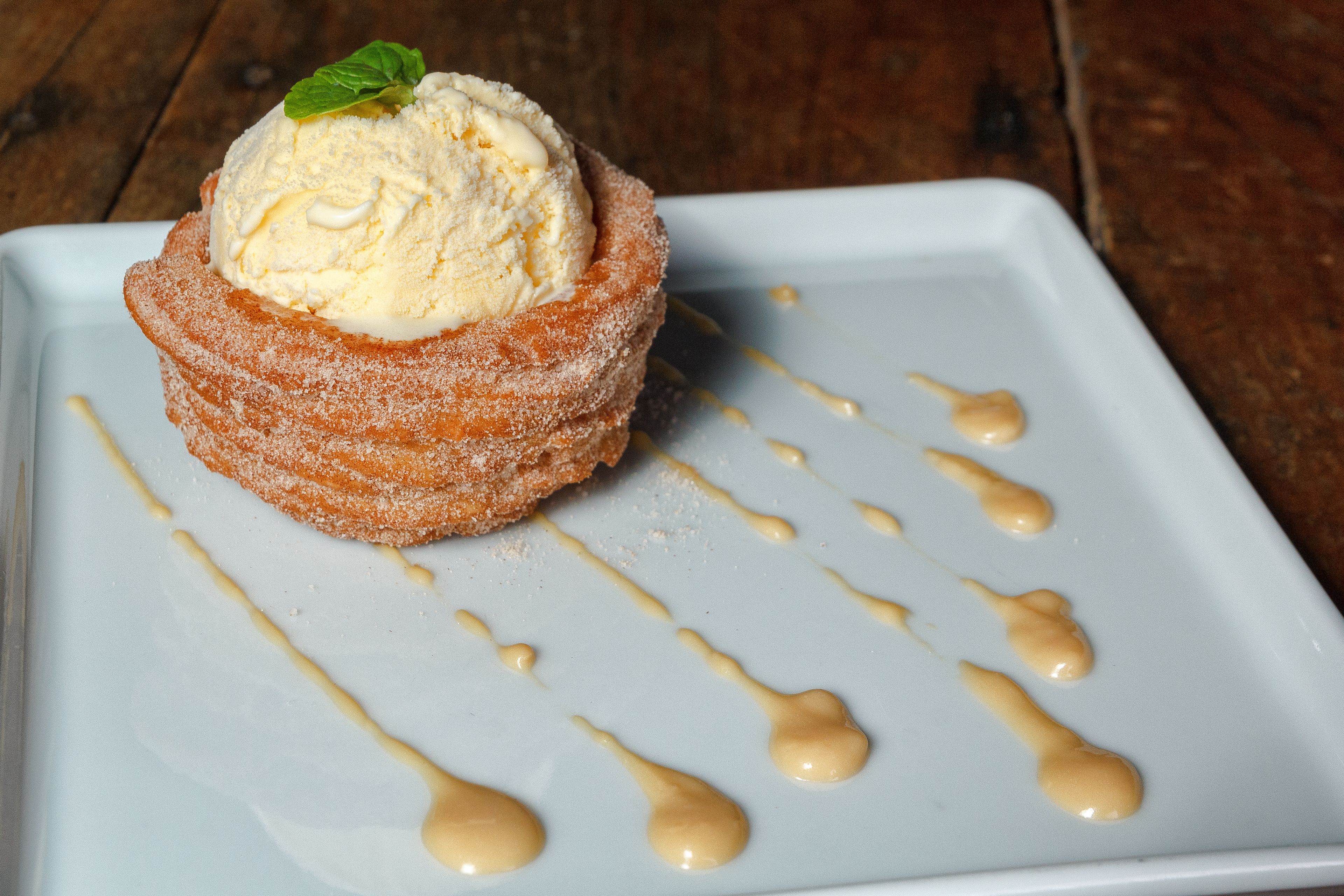 Un dessert composé d’une boule de glace, saupoudrée de sucre glace et nappée d’une sauce rappelant le caramel.