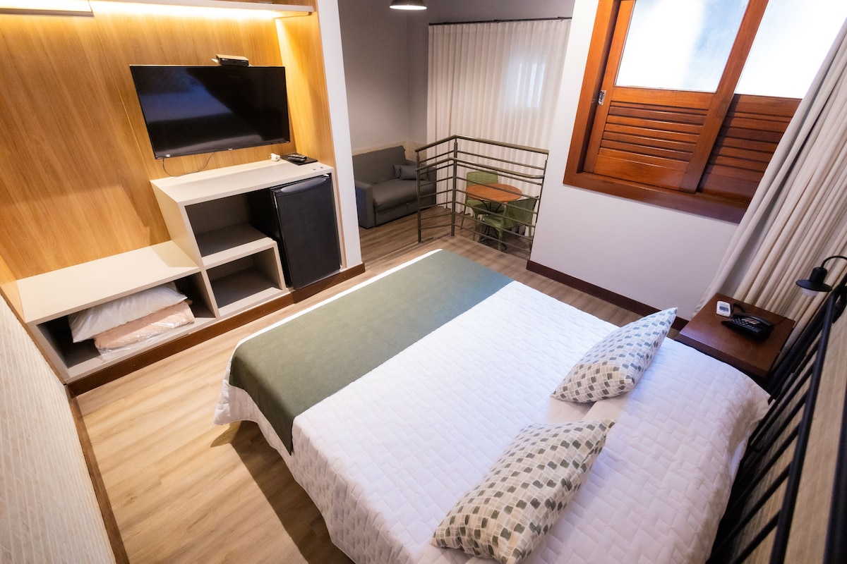 A hotel room with a bed, a TV, a desk, a sofa, and a balcony.