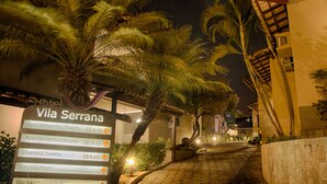 A nighttime view of Villa Serrana hotel with a sign indicating room availability and amenities.