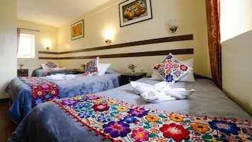 A hotel room with two beds, each with a colorful floral bedspread, a nightstand with a vase of flowers, and a painting on the wall.
