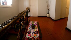 A room with a wooden bench, a floral tablecloth, a vase with flowers, and a door in the background. - Samay Inka Inn (Cusco)
