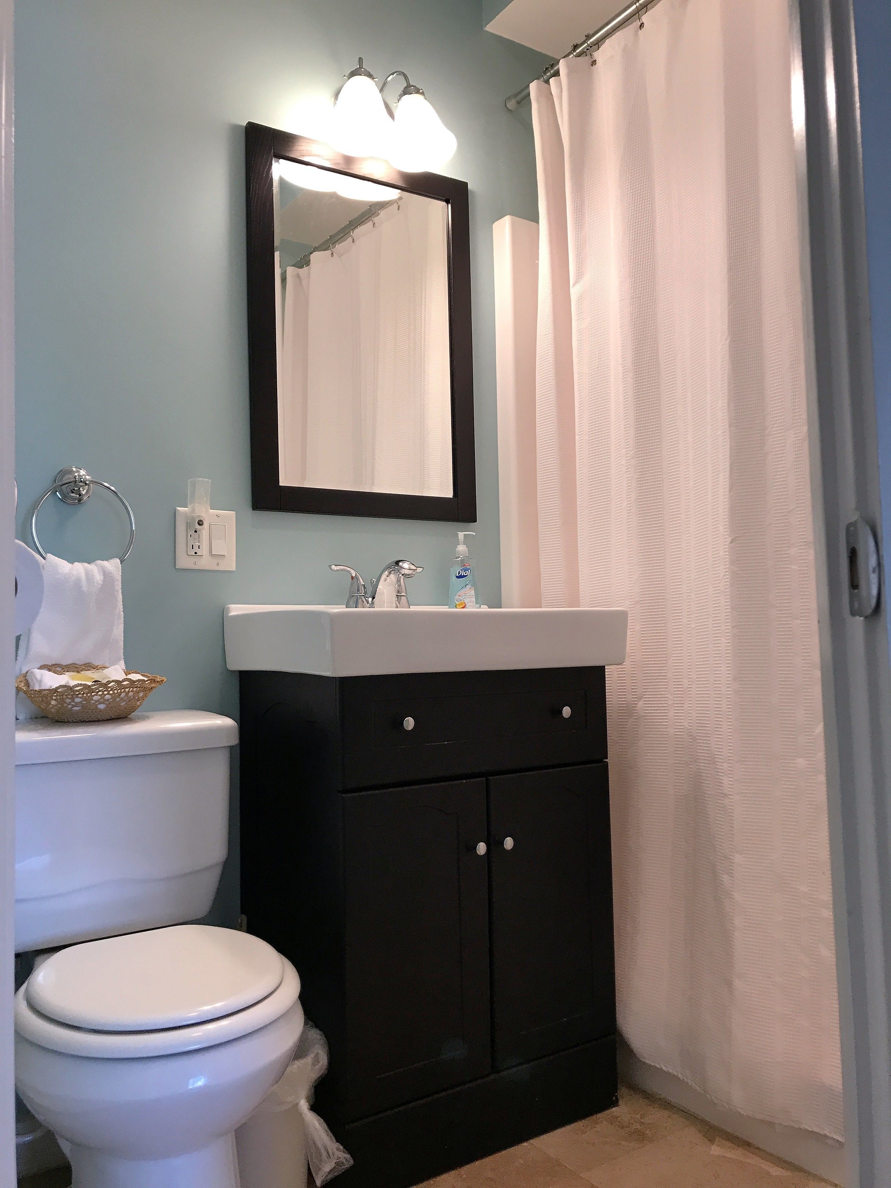 A bathroom with a toilet, sink, mirror, and a shower curtain.