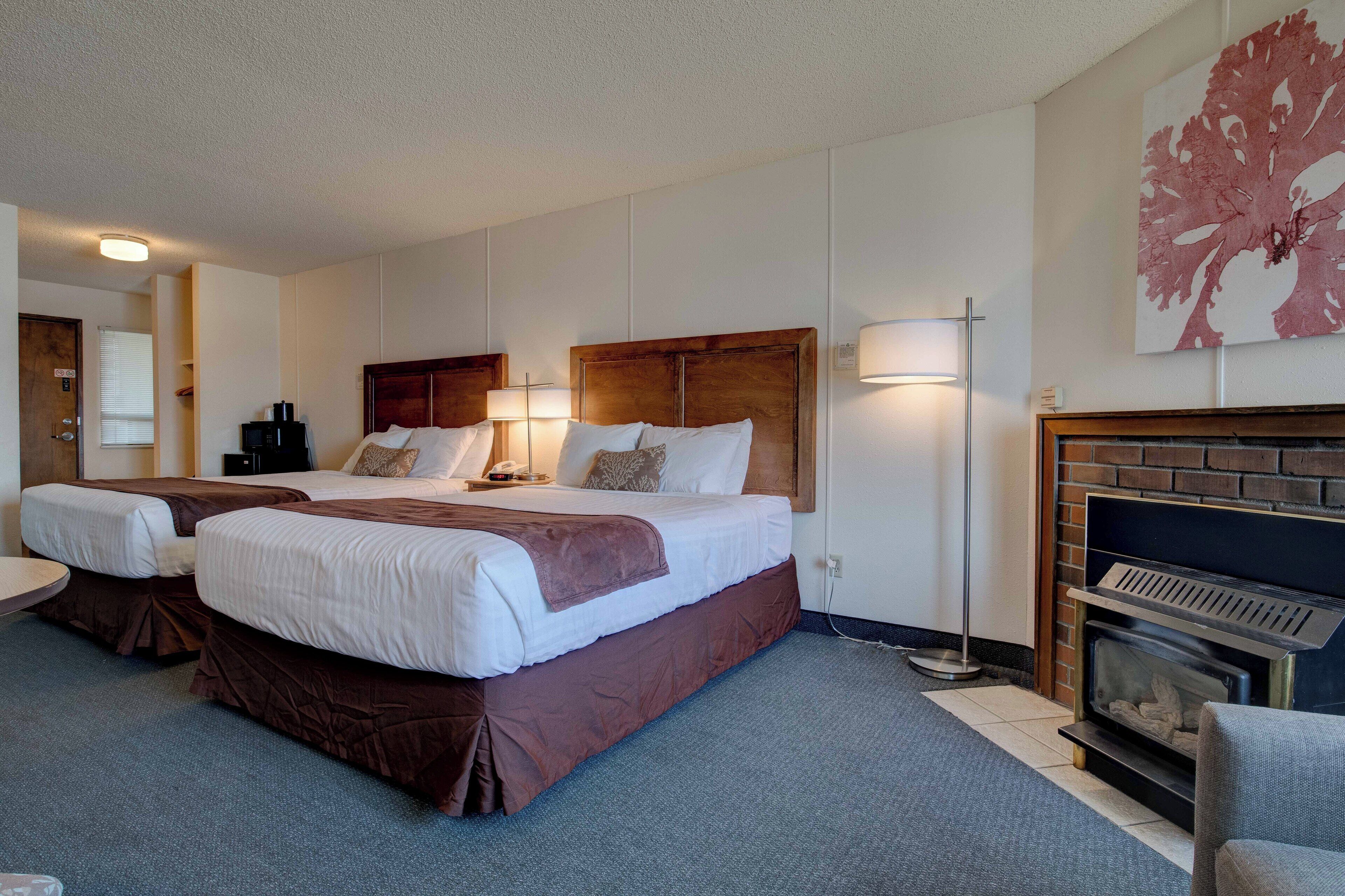 Ett hotellrum med två sängar, en öppen spis och ett stort konstverk på väggen.