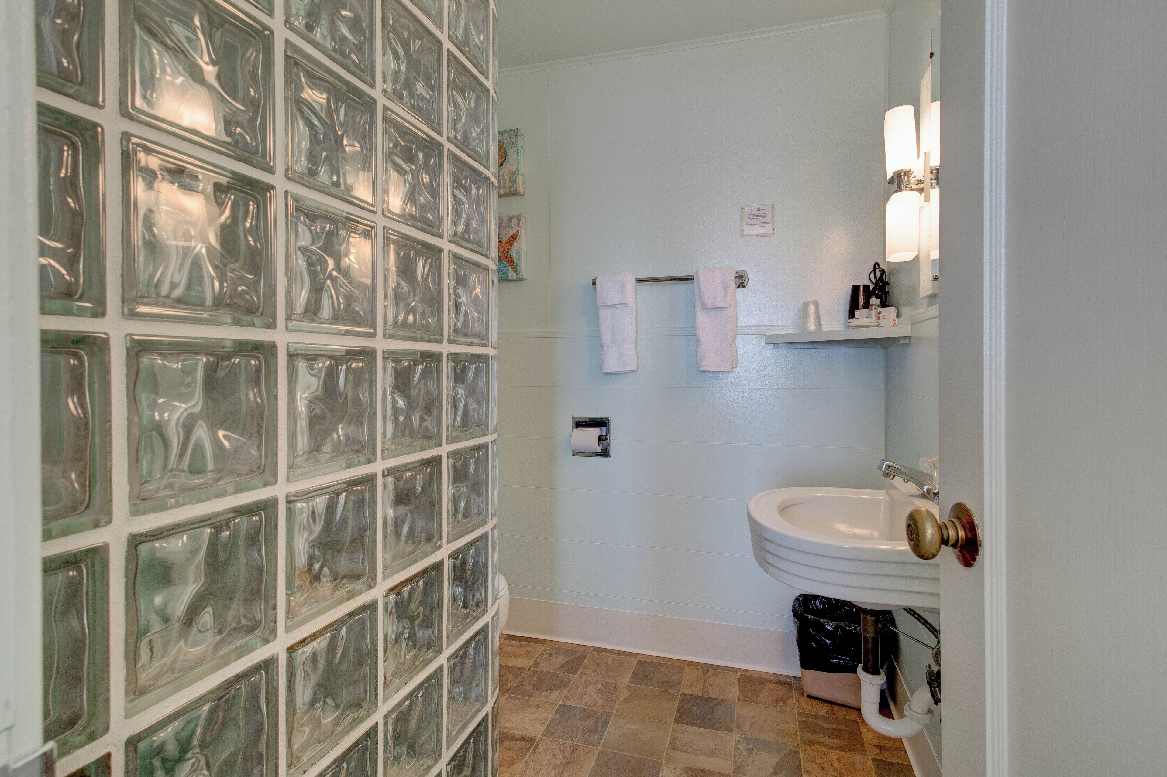 Ein Badezimmer mit einer Glasblockwand, einem weißen Waschbecken und einer Toilette.