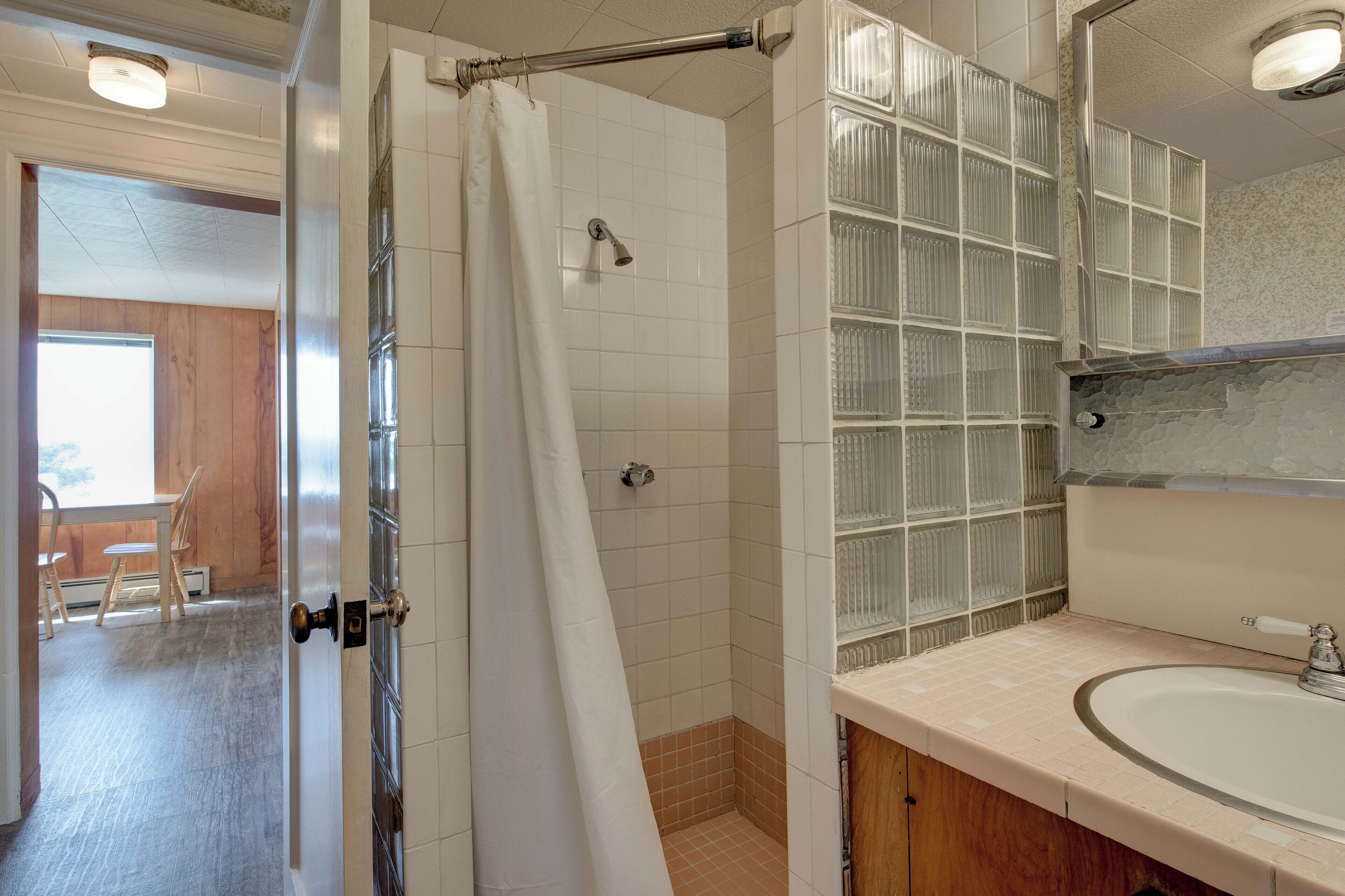 Un baño con ducha, lavabo y espejo.