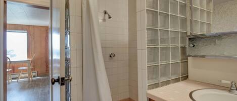 A bathroom with a shower, a sink, and a mirror.