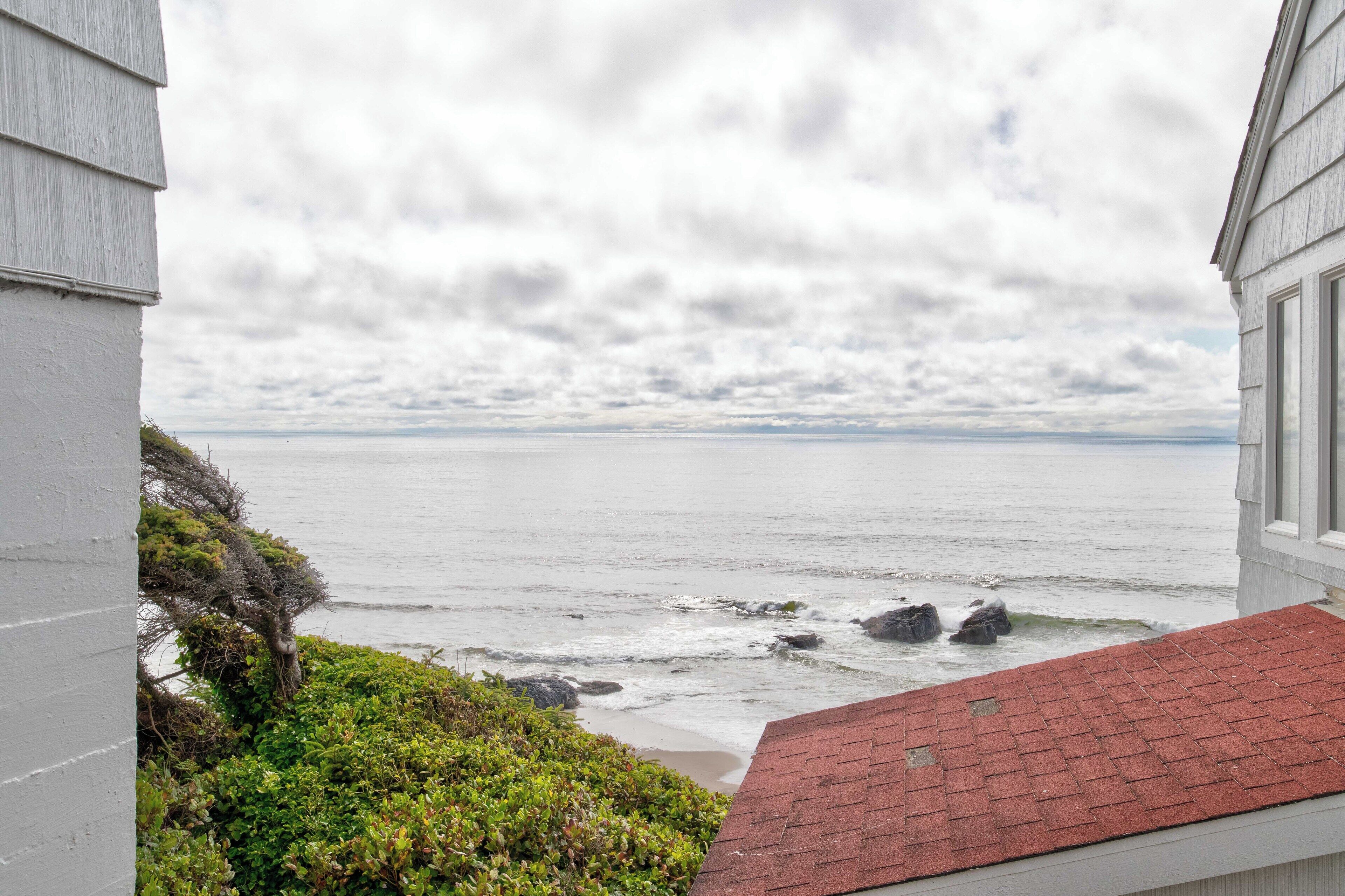 Une vue sur la côte, prise depuis un bâtiment dont le toit est rouge, avec l’océan et un ciel nuageux en toile de fond.