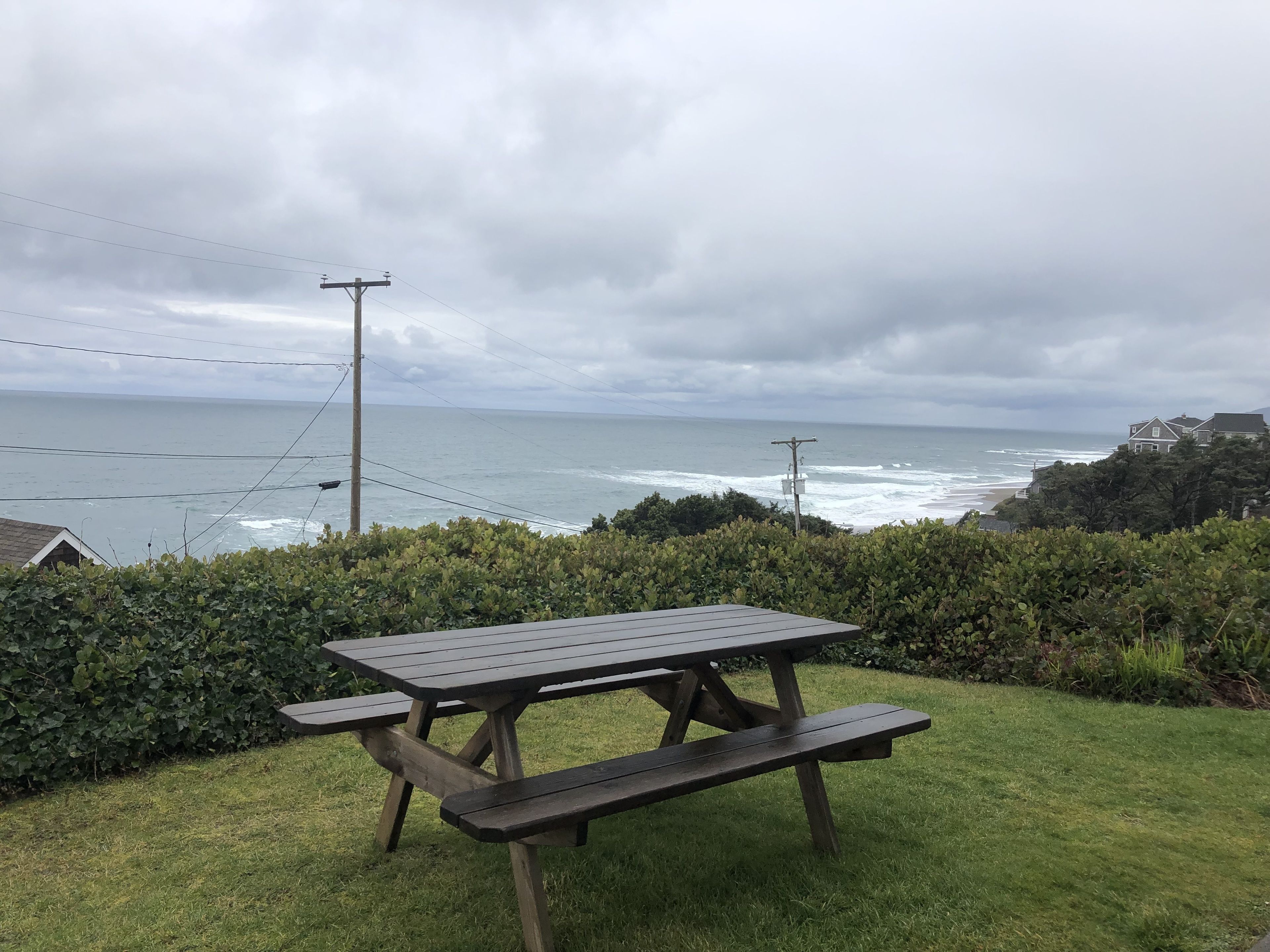 Ein Picknicktisch mit Bänken auf einer Rasenfläche mit Blick aufs Meer.