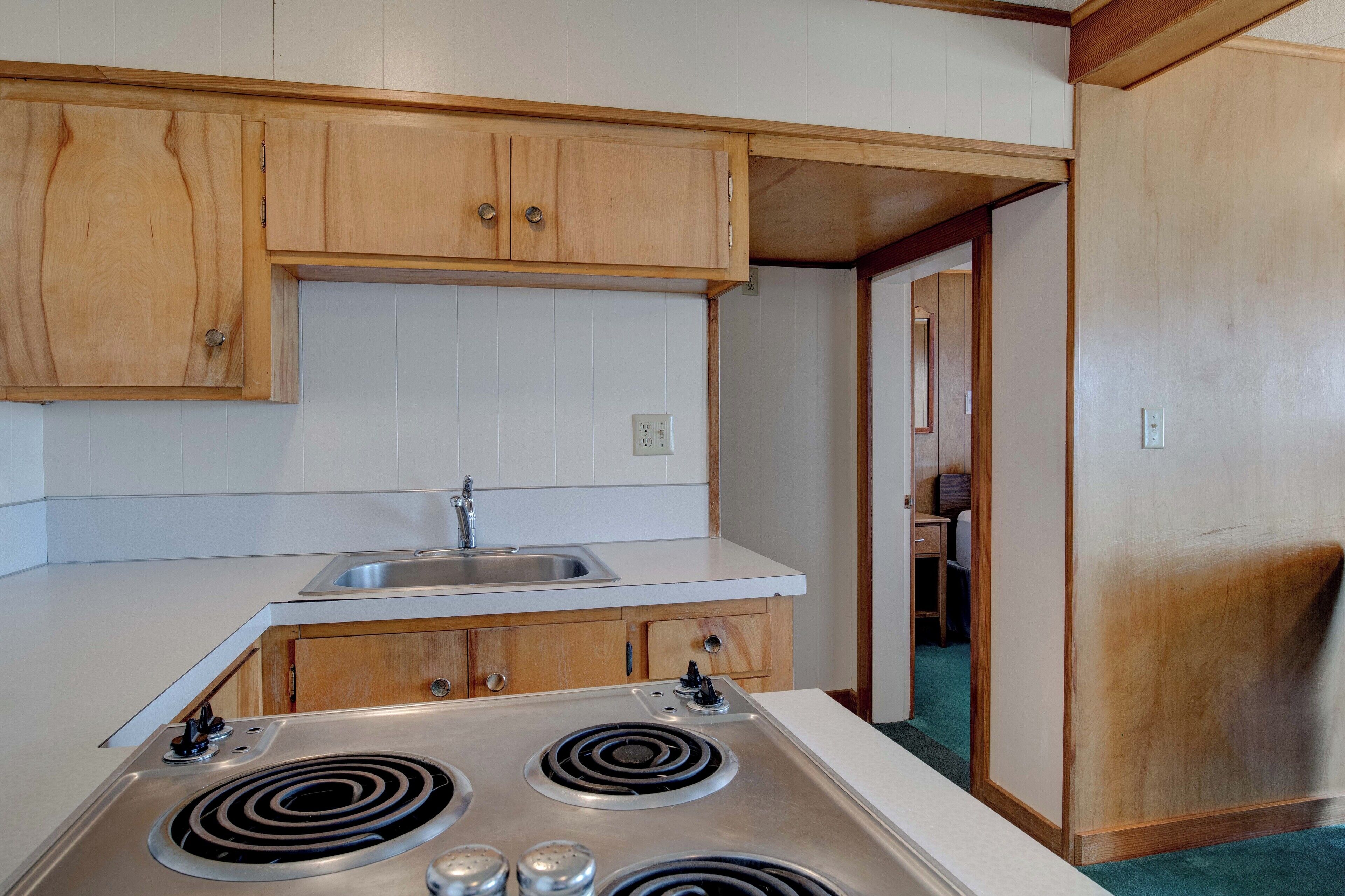 A compact kitchen with wooden cabinets, a stainless steel sink, and a built-in stovetop.