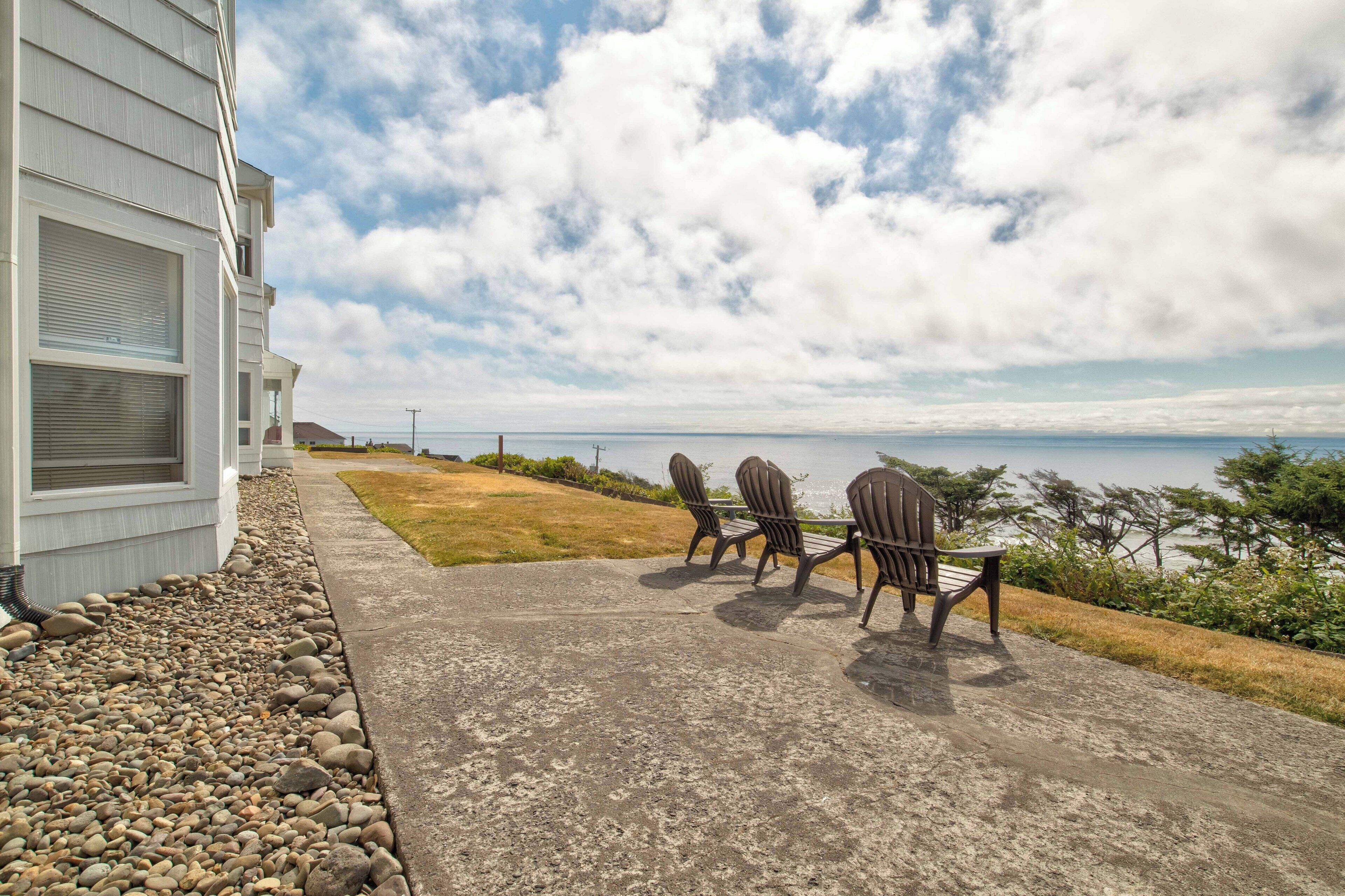A patio with outdoor furniture and a view of the ocean.