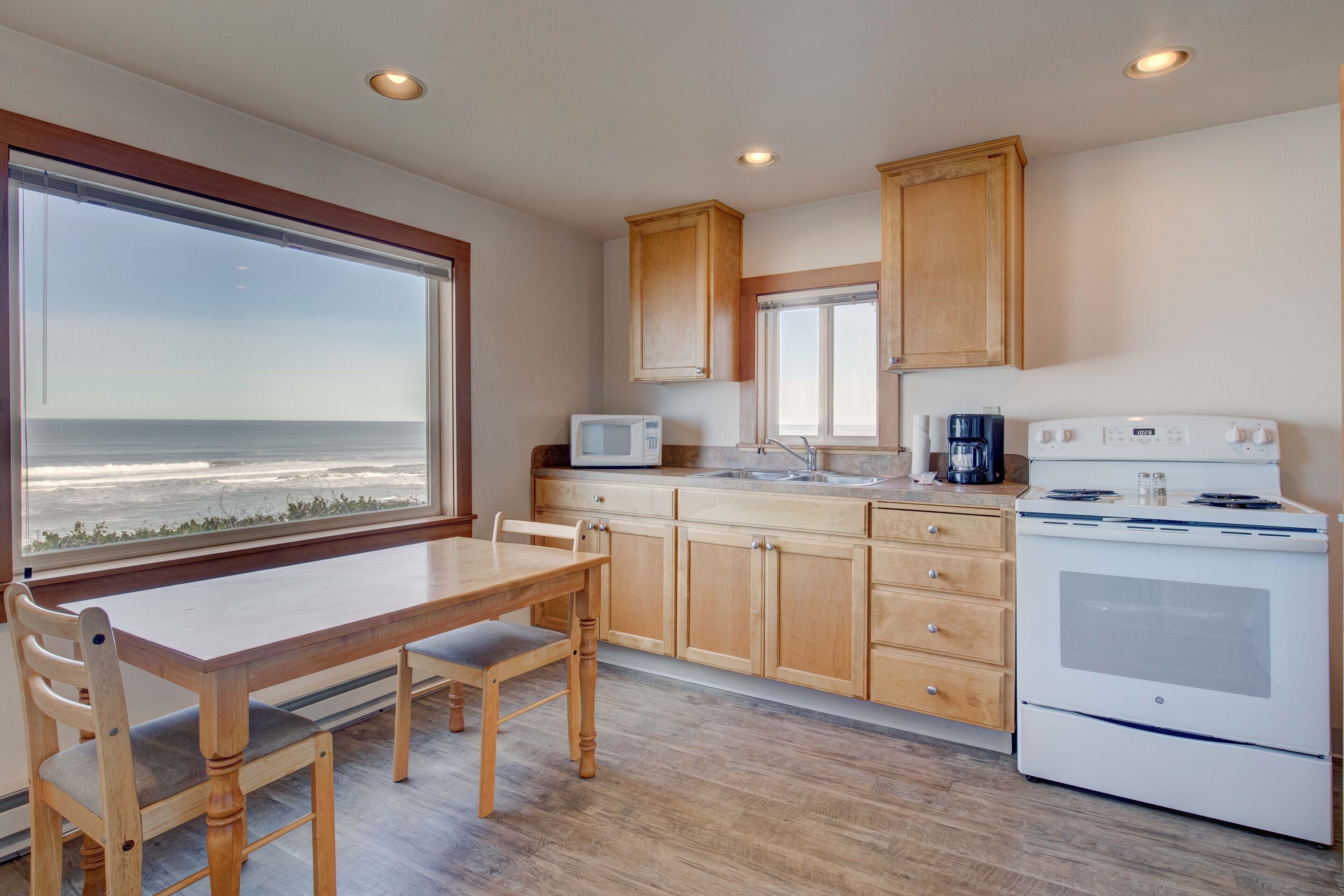A kitchen with wooden cabinets, a white stove, and a view of the ocean through large windows.