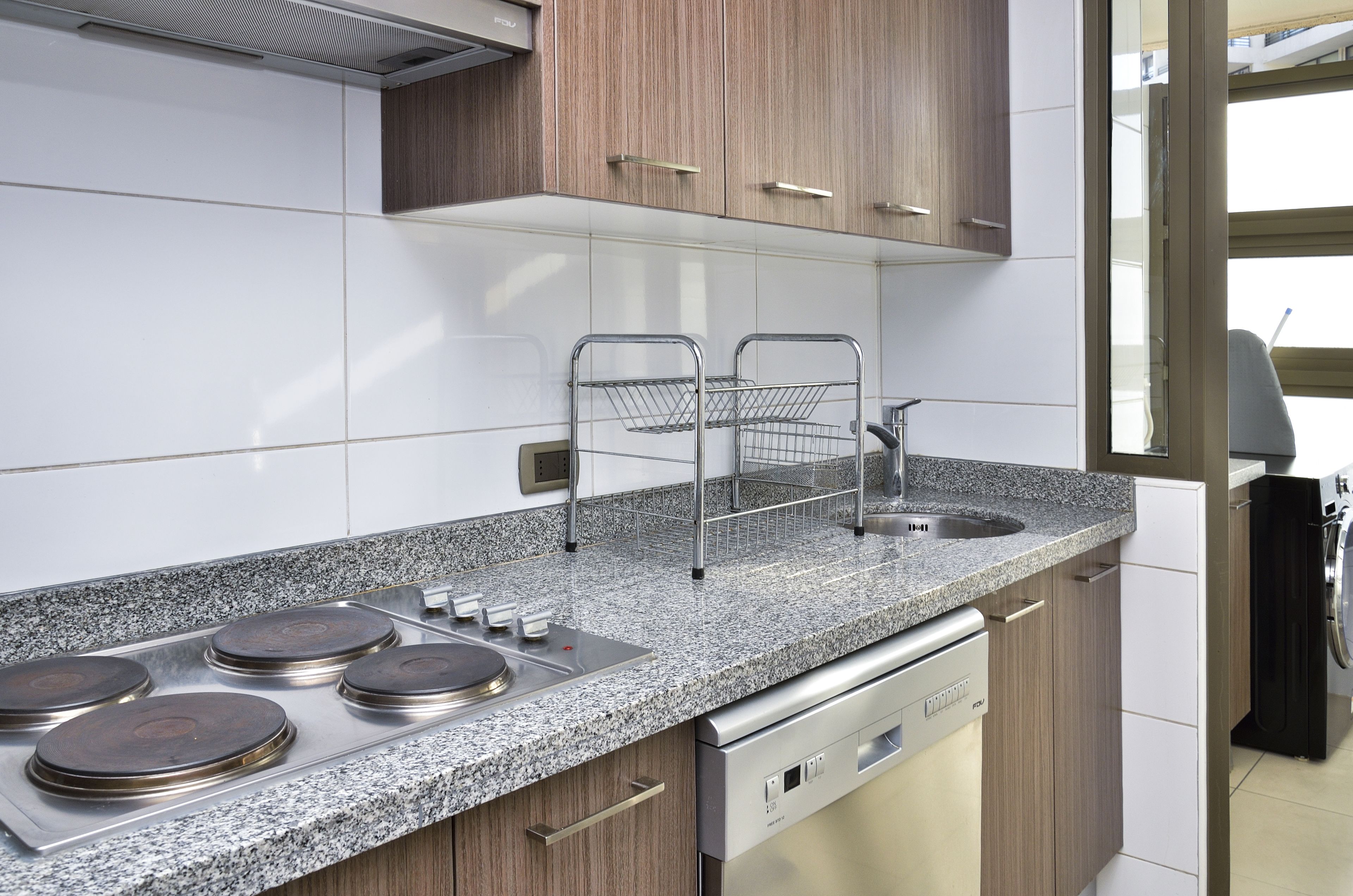 Una cocina moderna con encimeras de granito, electrodomésticos de acero inoxidable y armarios de madera.