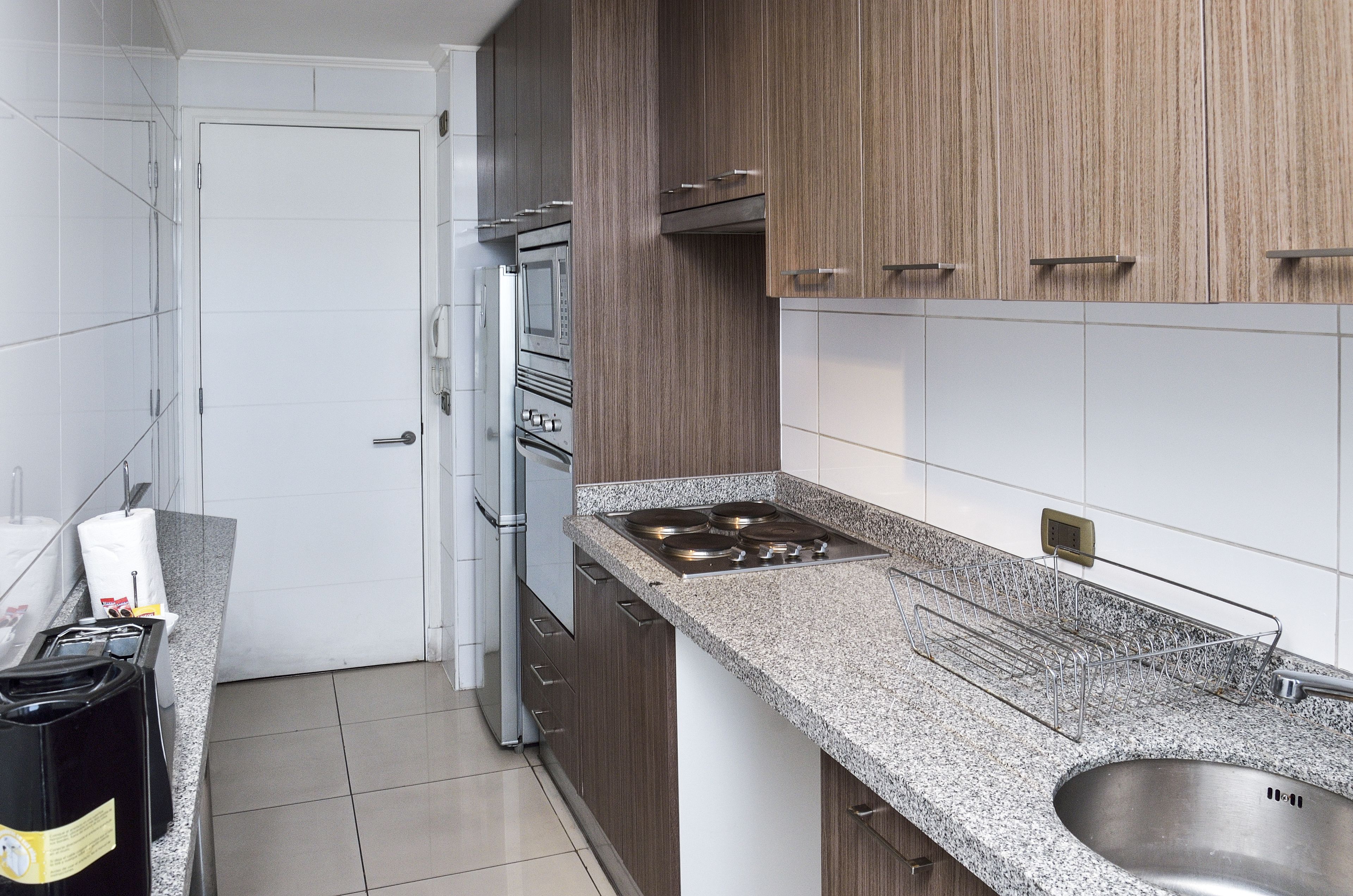 A modern kitchen with stainless steel appliances, a granite countertop, and wooden cabinets.