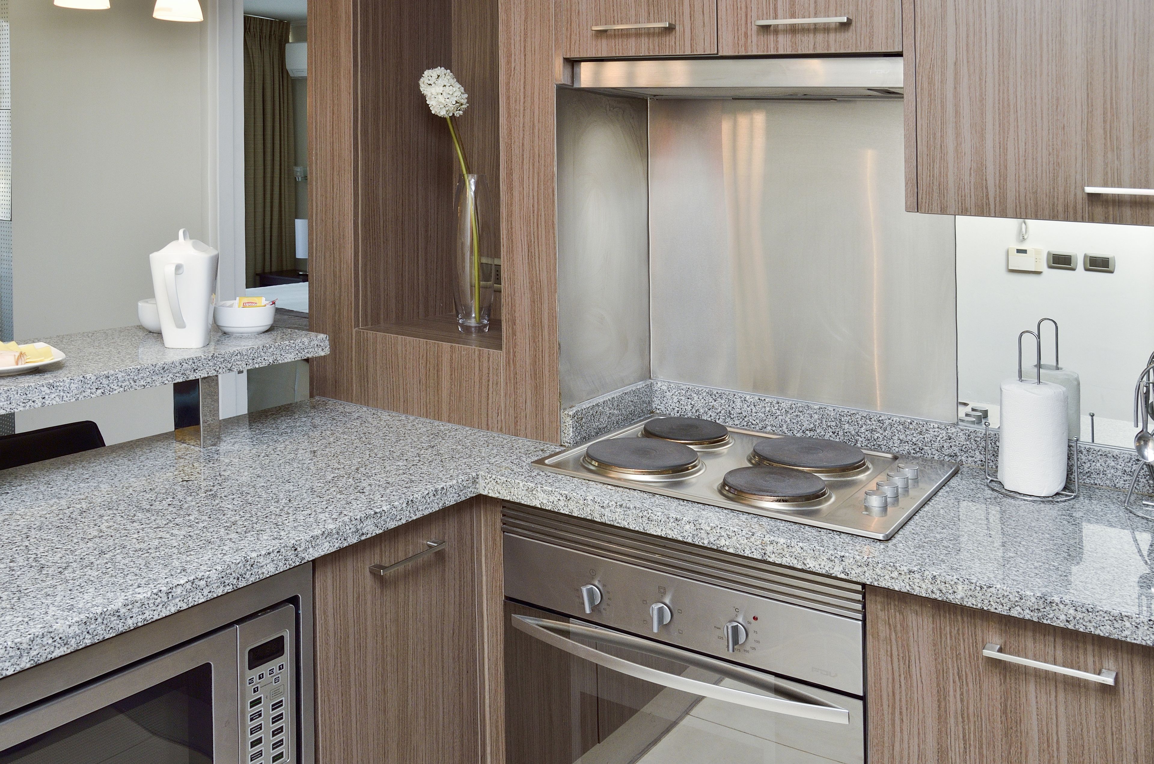 A modern kitchen with granite countertops, stainless steel appliances, and wooden cabinetry.