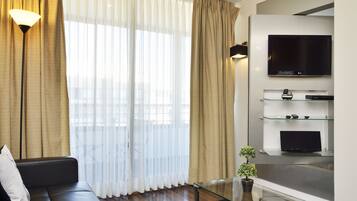 Relax in this stylish living room with a black leather sofa, glass coffee table, and wall-mounted TV.