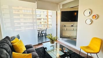 Relax in this stylish living room with a sofa, armchair, and flat-screen TV, plus a balcony with a view.