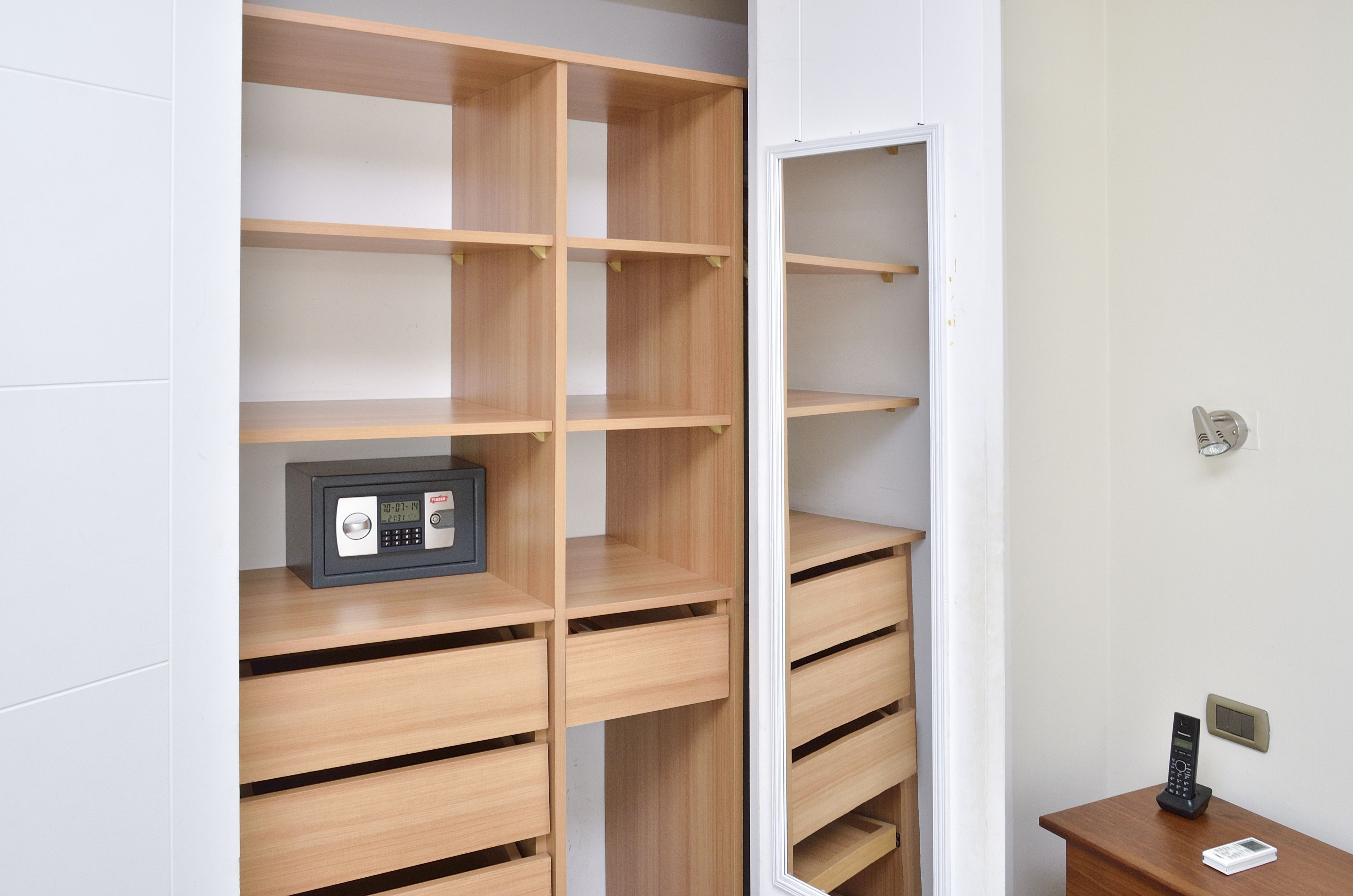 Ein Zimmer mit einem Holzschrank, einem Safe und einem kleinen Tisch mit Telefon.