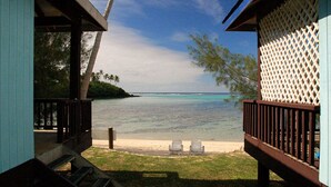 A beach view from a wooden deck with two lounge chairs facing the ocean. - Tianas Beach (Rarotonga)