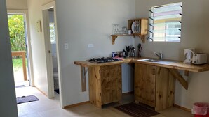 A kitchen with a wooden countertop, a sink, and a window with blinds. - Tianas Beach (Rarotonga)