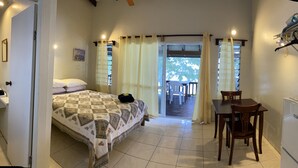 A bedroom with a bed, a desk, a chair, a sink, and a window with curtains. - Tianas Beach (Rarotonga)
