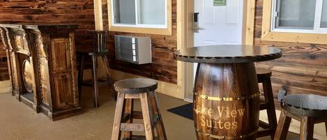 A rustic interior with wooden furniture, including a bar stool and a table with 'Lake View Suites' engraved on it.
