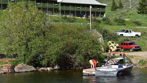 A building with a green facade and multiple balconies, situated near a body of water with boats docked. - Lake View Suites (West Yellowstone)