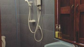 A bathroom with a shower, a toilet, and a mirror.
