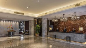 A modern hotel lobby with a marble reception desk, a large potted plant, and a wall-mounted display. - North star Hangzhou Expo Center Hotel (Hangzhou)