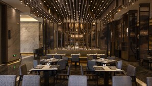 A modern restaurant with a central bar, multiple dining tables, and a unique ceiling design. - North star Hangzhou Expo Center Hotel (Hangzhou)
