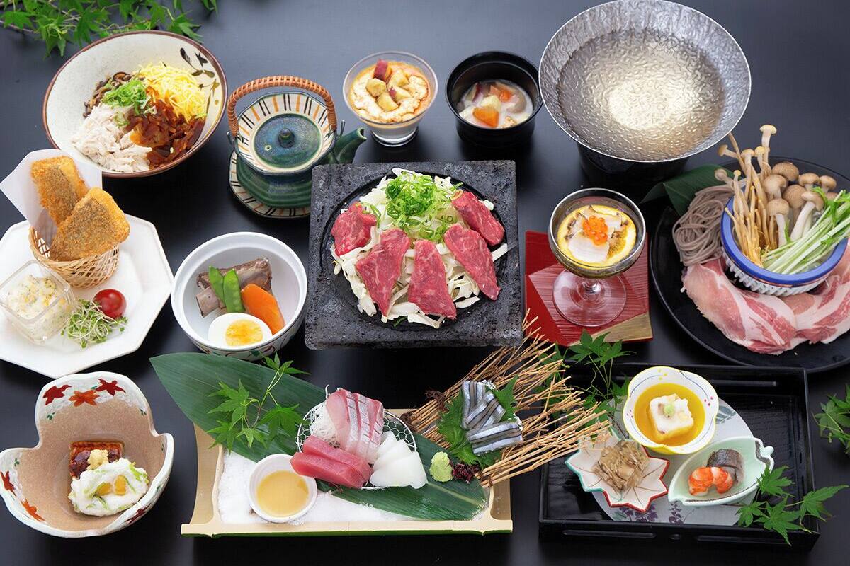 Une variété de plats japonais, notamment des sushis, des sashimis et des tempuras, présentés sur une table sur fond sombre.