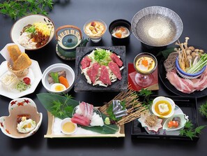 Variedad de platos japoneses, incluyendo sushi, sashimi y tempura, dispuestos sobre una mesa con fondo oscuro.
