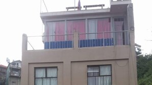 A multi-story building with a flat facade, multiple windows with white frames, and red awnings. - Kensington Garden BNB (Baguio)