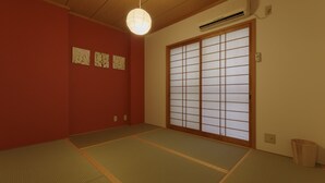 A traditional Japanese room with tatami flooring, a shoji screen door, and a hanging light fixture. - Kokoro House (Osaka)