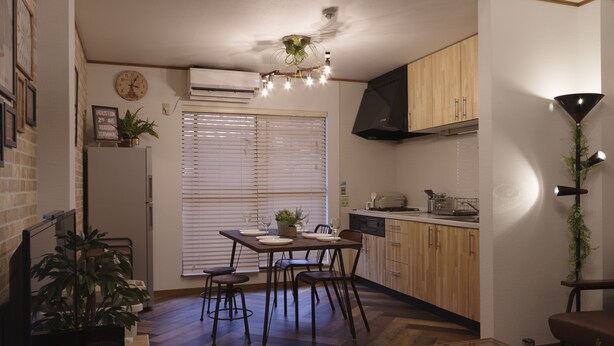 A compact kitchen with wooden cabinets, a dining table with chairs, and a ceiling fan. - Kokoro House (Osaka)