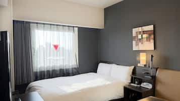 Habitación de hotel con una cama grande, una mesita de noche con lámpara, un cuadro en la pared y una ventana con cortinas de encaje.