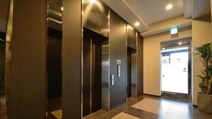 Área de elevador moderna com paredes metálicas e uma planta em vaso.