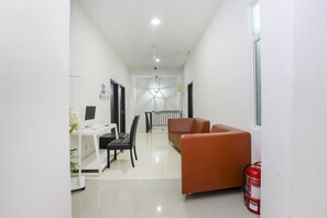 Enter a well-appointed hallway leading to a cozy living area with a desk, sofa, and comfortable seating.