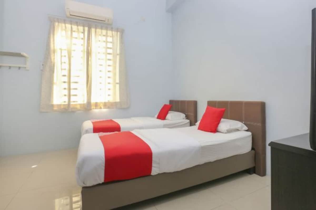 Una habitación de hotel con dos camas, una ventana con cortinas, un aire acondicionado y un televisor.