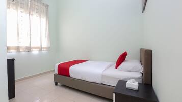 A hotel room with a bed, a bedside table, a window with curtains, and a wall-mounted air conditioner.