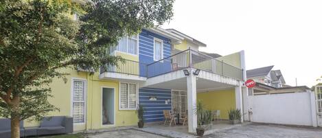 A two-story house with a balcony, a porch, and a small garden area.