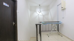 Un couloir avec une porte en bois sombre, un luminaire au plafond et une boîte électrique fixée au mur.