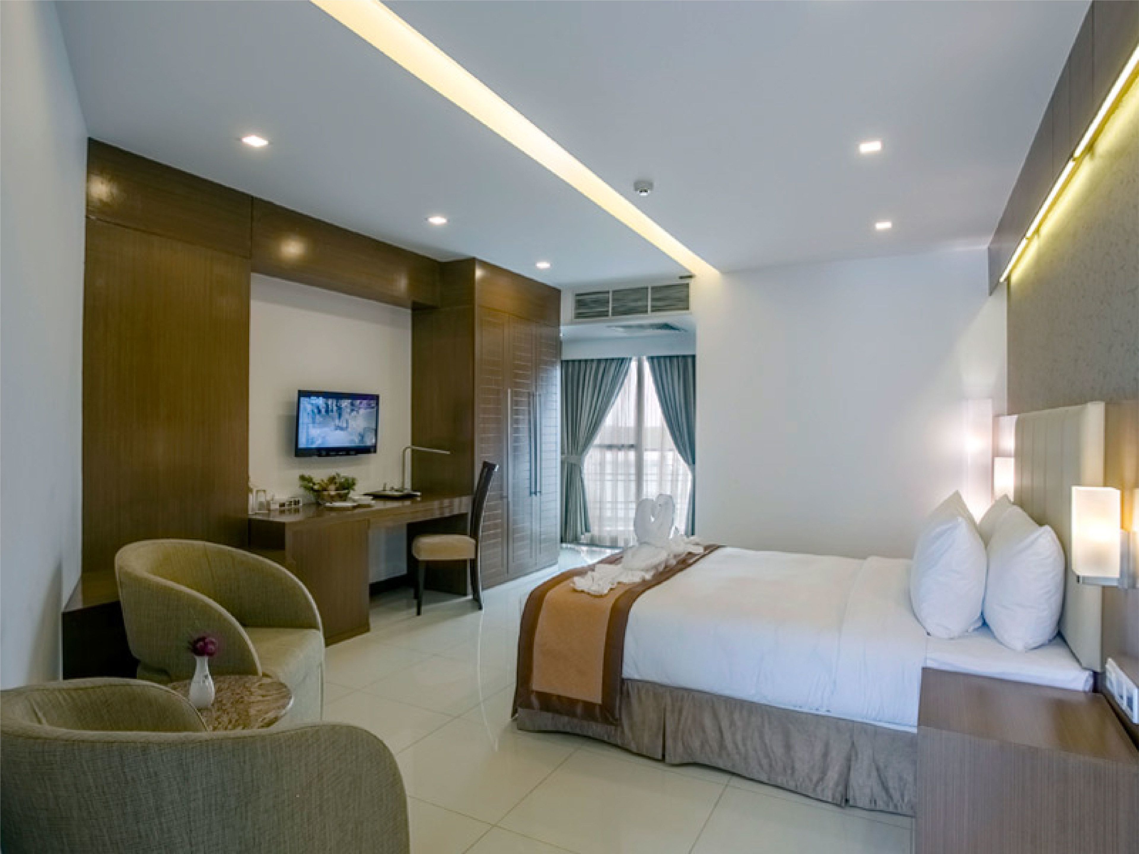 A modern hotel room with a bed, a desk, a chair, and a television.