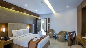 A modern hotel room with a large bed, a desk, two chairs, and a small table. - BCDM Rajendrapur (Pirozali)